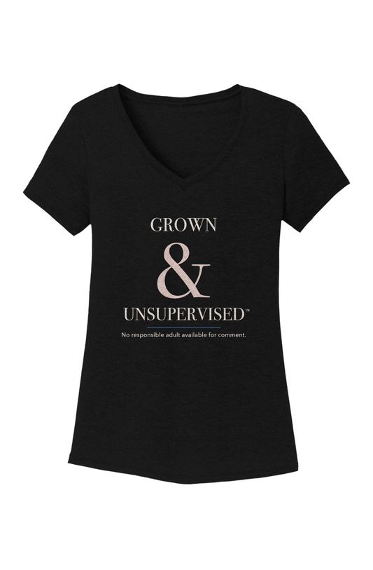 Black women's V-neck tee, front view, with Grown & Unsupervised™ printed in ivory serif lettering, an oversized rosy-champagne ampersand, a thin royal-blue rule, and the line No responsible adult available for comment.