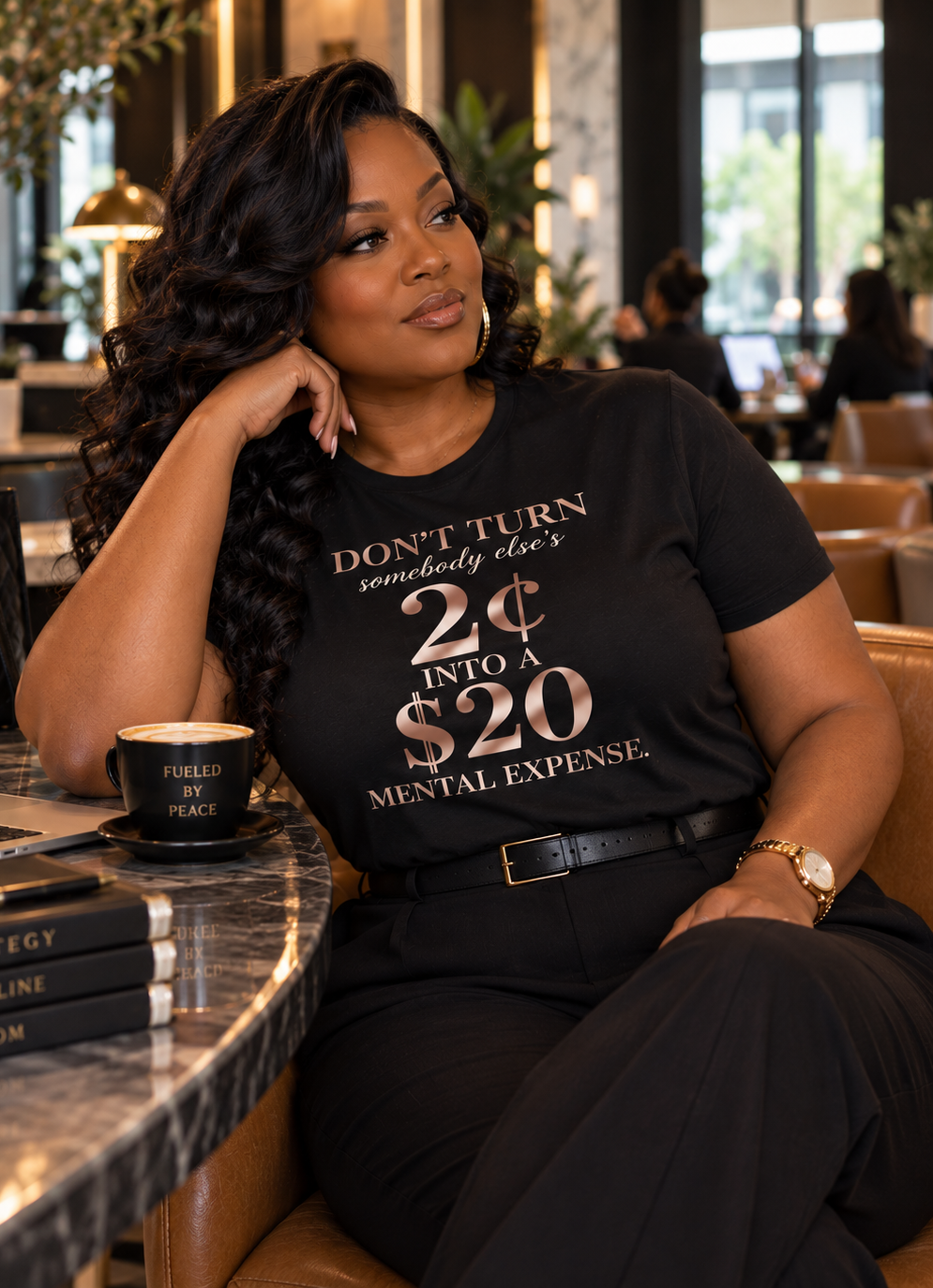 Woman in the black 2¢ Mental Expense Tee seated at a cafe table